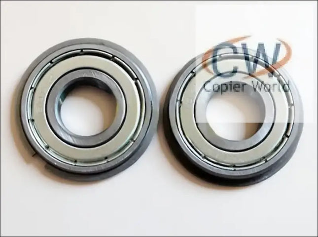 Two Canon IR5075 LOWER BERING metal ball bearings, each with a central hole, identical circular shapes, and a smooth metallic finish, are placed side by side on a white surface.