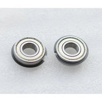 Two Canon IR5075 LOWER BERING metal components are side by side on a textured surface. Each has a central hole, metallic outer rings with grooves, and visible seams around the edge. Brand: Canon.